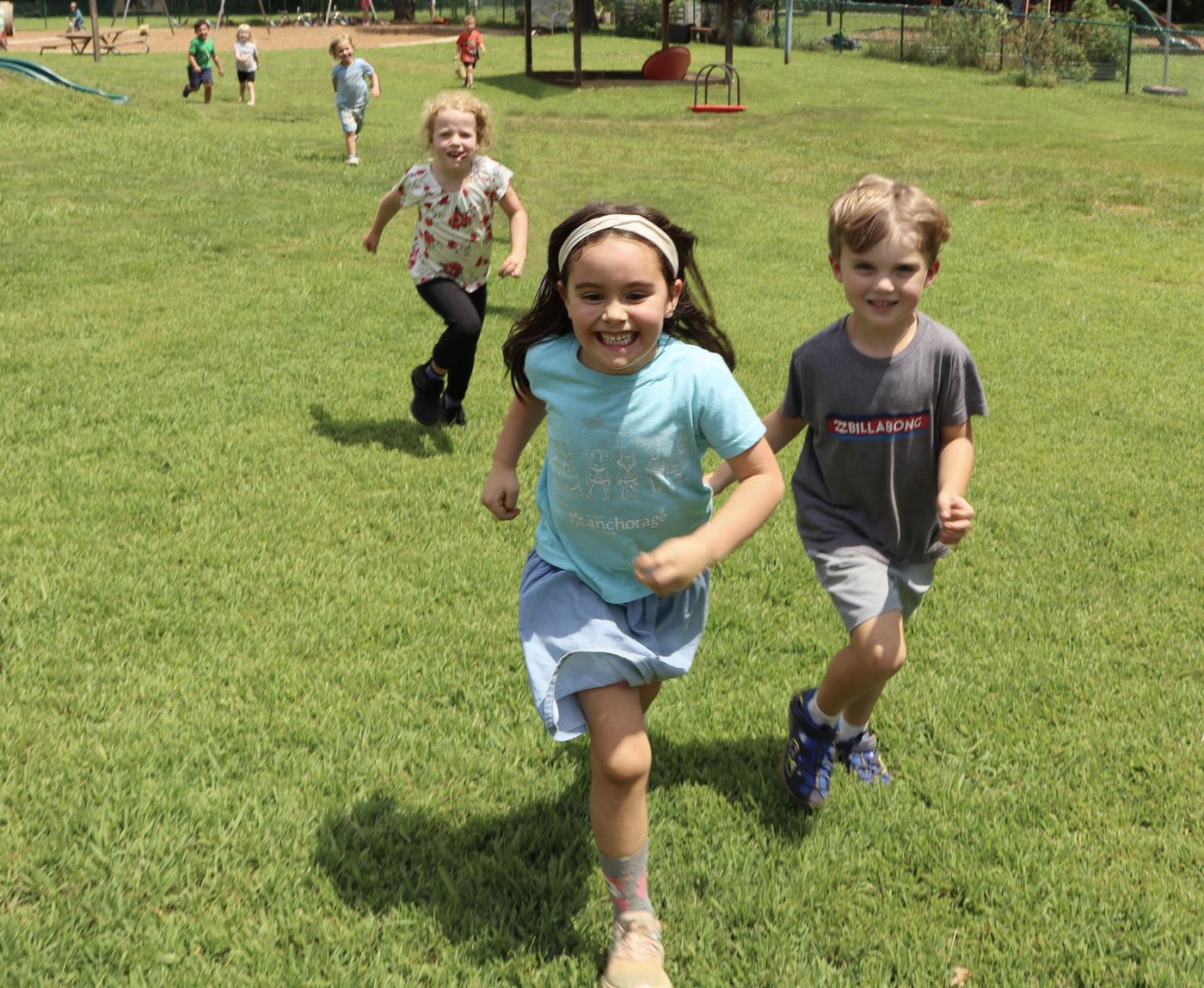 Primary students running and smiling across the playground field