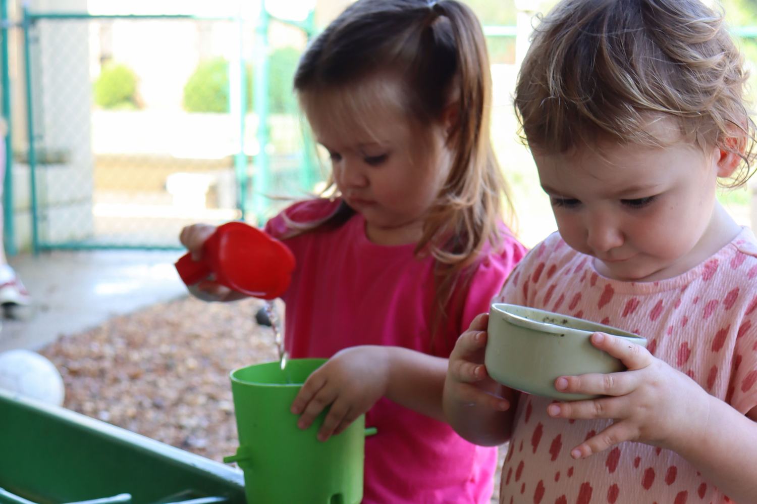 Two toddlers pouring and scooping at a sensory water table